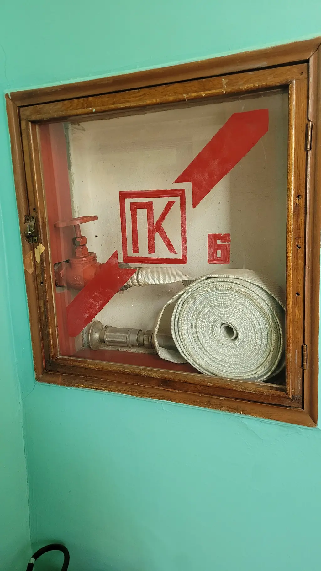 Пожарный кран в настенном шкафу с маркировкой «ПК»: клапан на трубопроводе, рукав в скатке и ручной ствол. Фото: Artem Svetlov, CC0
