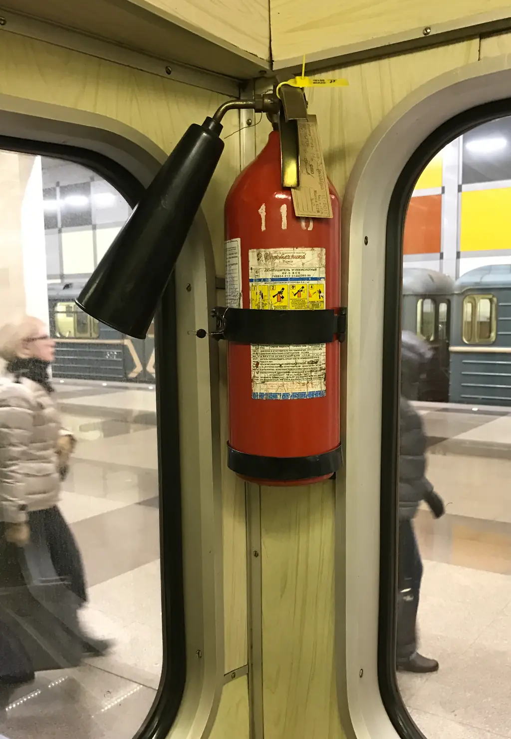 Углекислотный огнетушитель в вагоне метро: вместо шланга — чёрный раструб, манометра нет. Фото: Stolbovsky, CC BY-SA 3.0