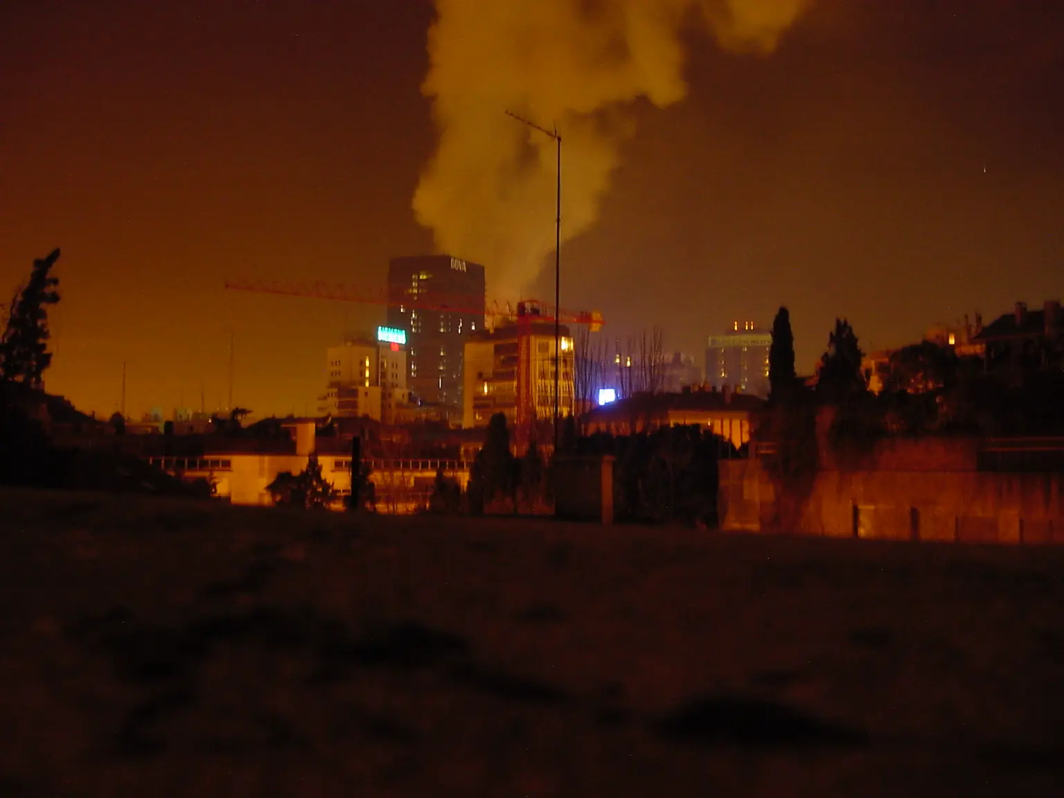 Мадрид, 13 февраля 2005 года, около трёх часов ночи: над кварталом поднимается подсвеченный столб дыма от горящей башни Windsor, на переднем плане стрела строительного крана. Фото: Orugachan, общественное достояние