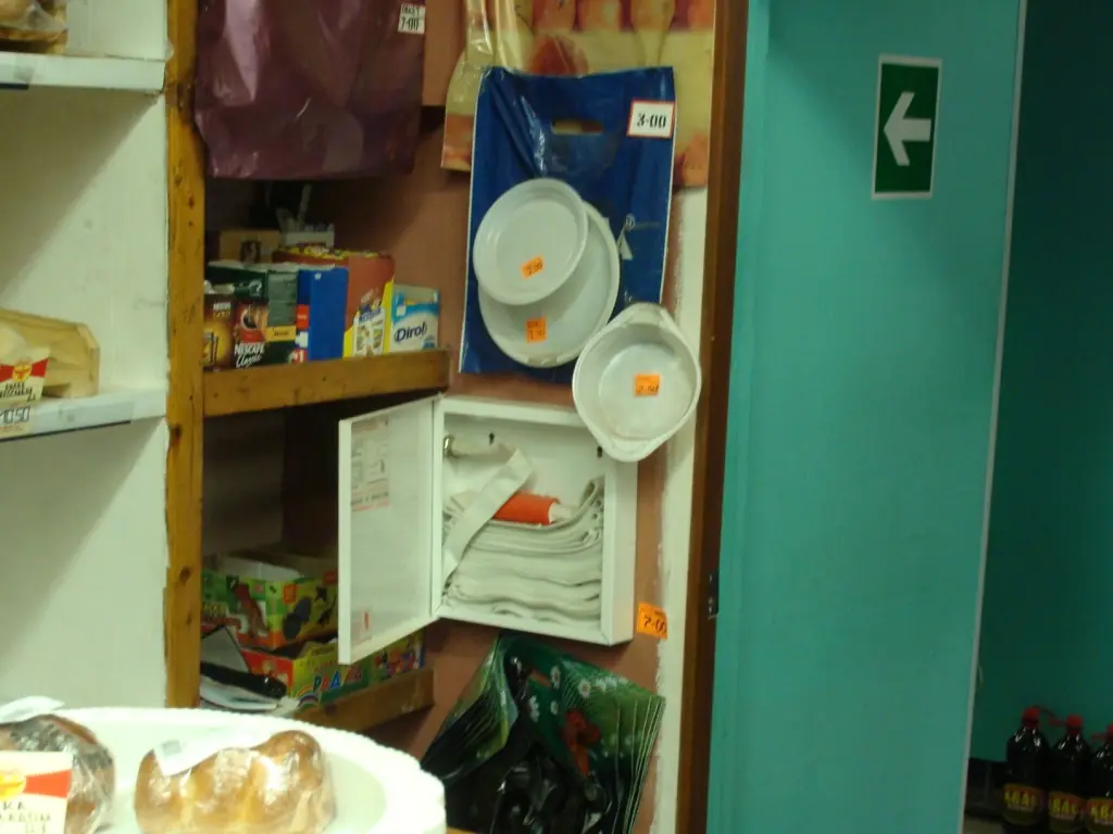 Маленький навесной шкаф с рукавом в магазине: дверца открыта, вплотную к шкафу стоят полки с товаром и висит посуда. Фото: Georg Pik, CC0